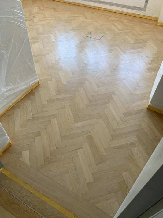 Frisch behandeltes Fischgrätparkett aus Eiche in einem hellen Wohnraum