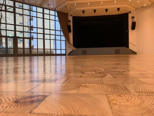 Gros plan sur un parquet en bois de cœur présentant des cernes annuels visibles dans une salle de spectacle