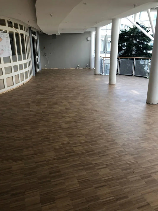 Parquet en mosaïque déjà poncé dans le hall d'entrée, avec ses colonnes et sa baie vitrée